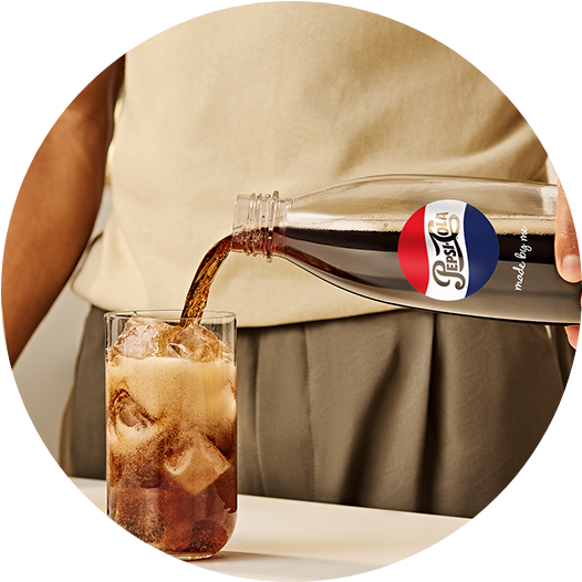 Mężczyzna nalewa własnoręcznie przygotowaną Pepsi z butelki SodaStream prosto do szklanki z kostkami lodu