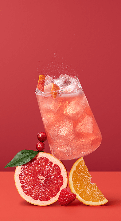 Wlewanie pomarańczowego napoju z dzbanka do butelki Sodastream na blacie